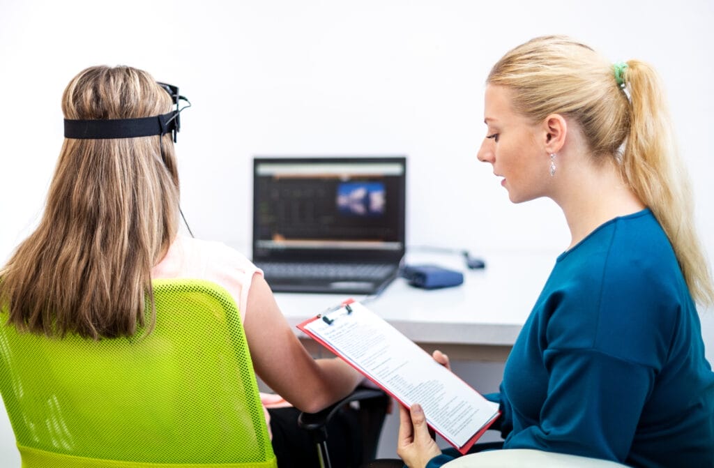 Young teenage girl and child therapist during EEG neurofeedback session.